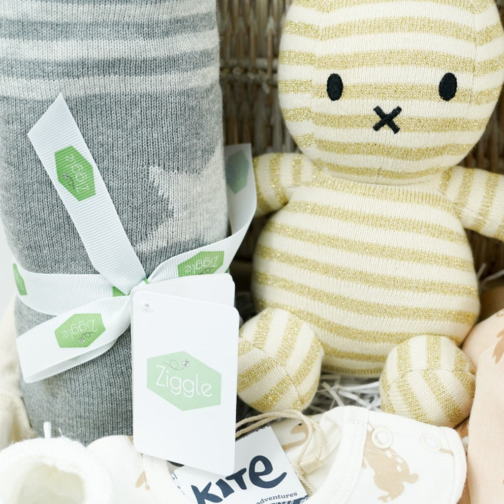 white wicker basket, grey star cotton baby blanket, gold and cream organic miffy, cream baby bodysuit with brown rabbits, caramel coloured sleepsuit with brown rabbit