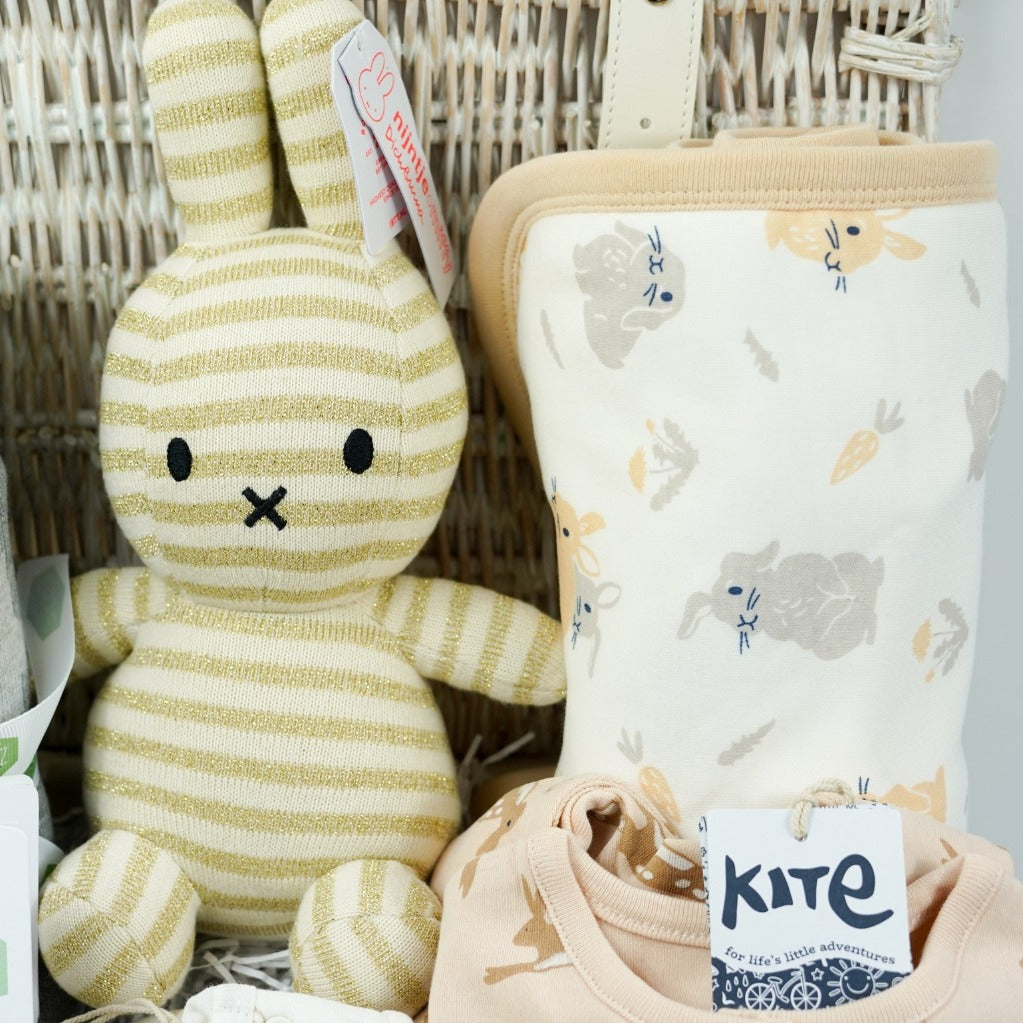 white wicker basket, grey star cotton baby blanket, gold and cream organic miffy, cream baby bodysuit with brown rabbits, caramel coloured sleepsuit with brown rabbit