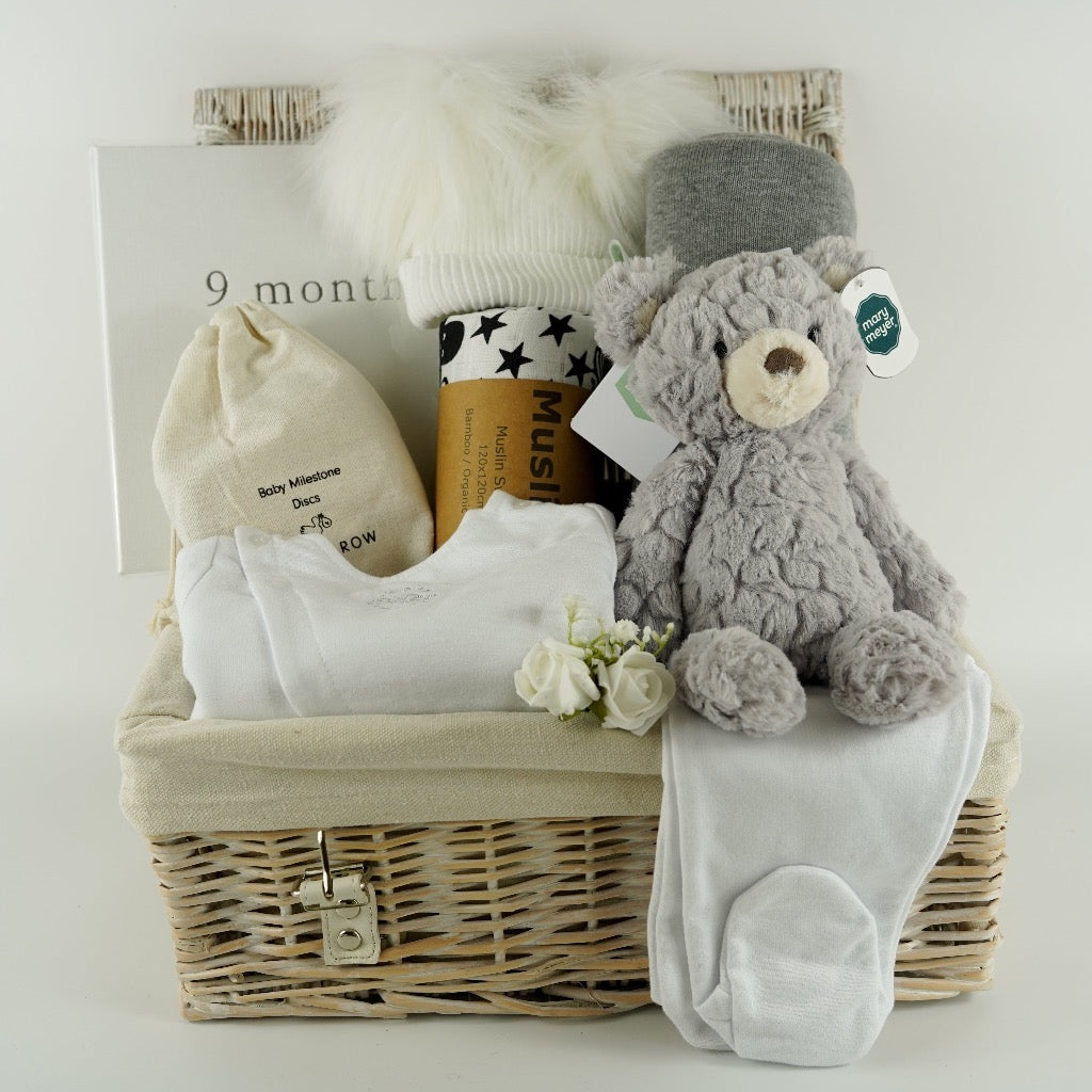 Pregnancy hamper basket with grey teddy, grey baby blanket with stars , black and white sensory baby swaddle, white baby hat with 2 Pom poms . White pregnancy journal. Pregnancy milestone discs, white baby clothing set includes jacket, bodysuit and leggings