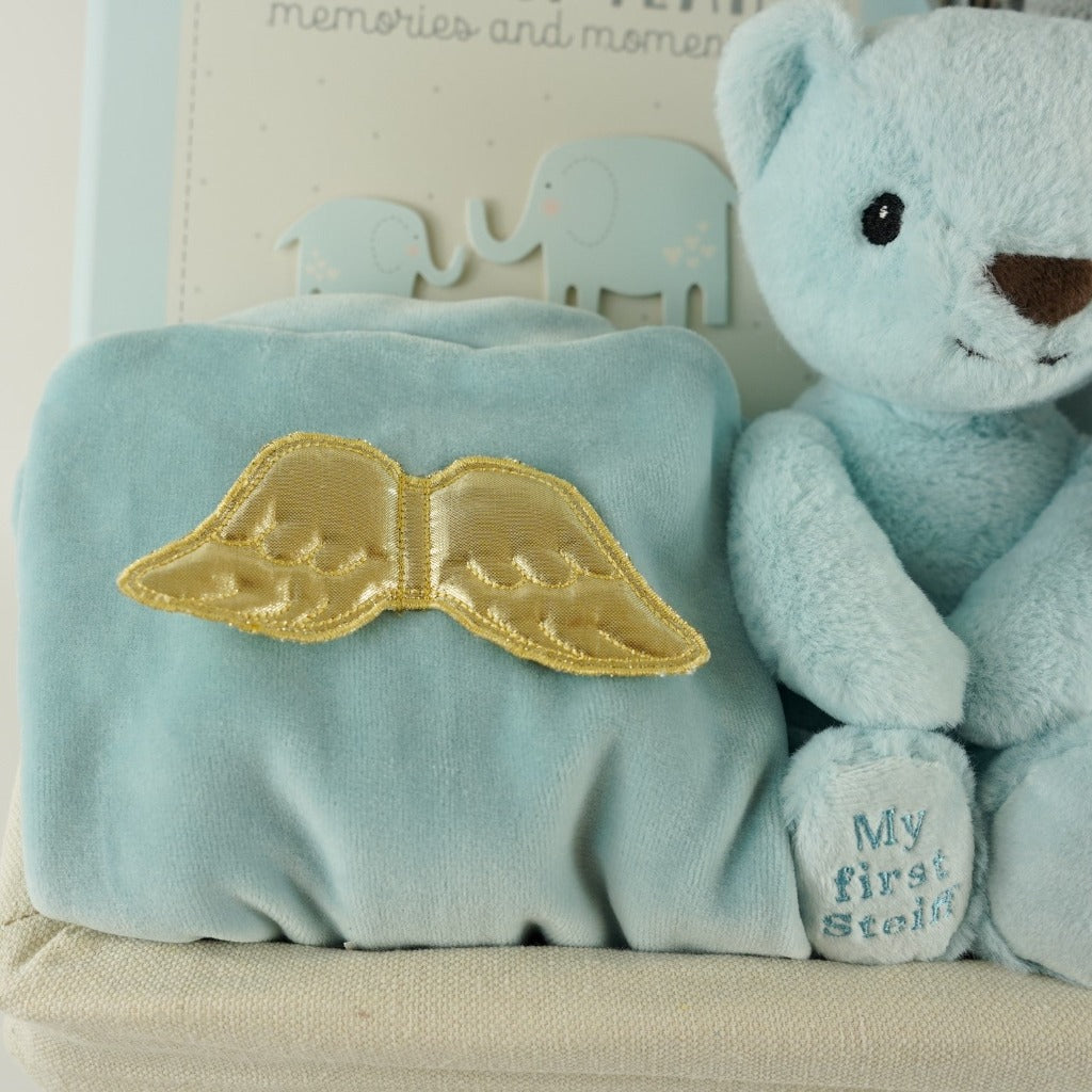 White wicker basket, angel wings blue velour sleepsuit, blue Steiff my first teddy, grey and white ziggle blanket, My first year record book