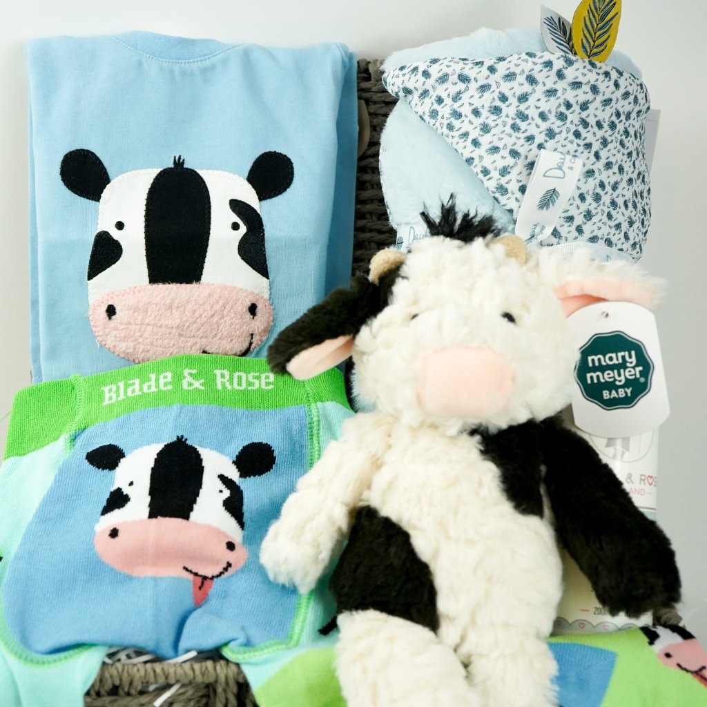 baby boy hamper, blue baby clothing set with long sleeved blue tshirt and leggings with cow on the bottom, baby toiletries, soft doudou baby blanket, baby socks