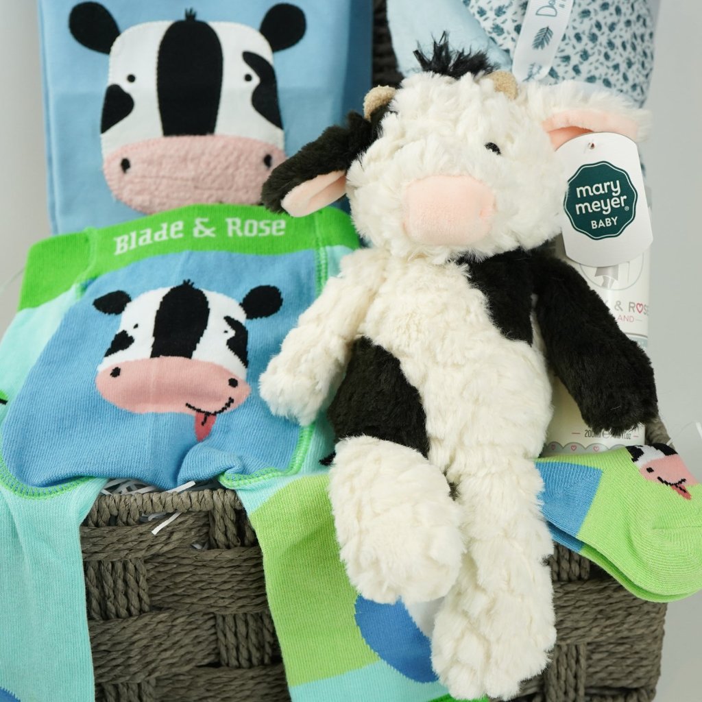 baby boy hamper, blue baby clothing set with long sleeved blue tshirt and leggings with cow on the bottom, baby toiletries, soft doudou baby blanket, baby socks