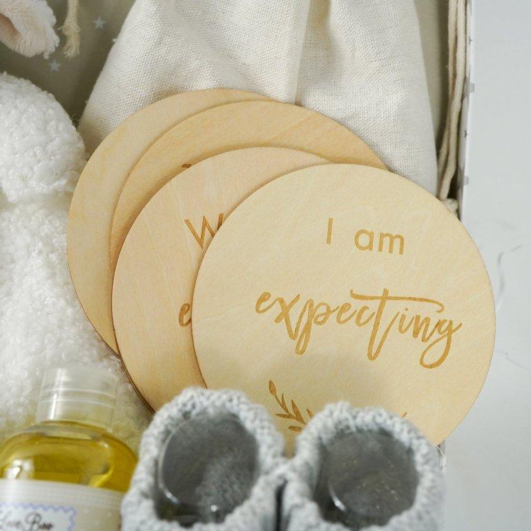 pregnancy hamper in a grey with white star case lamb comforter, grey booties, perineum oil, pregnancy milestone discs