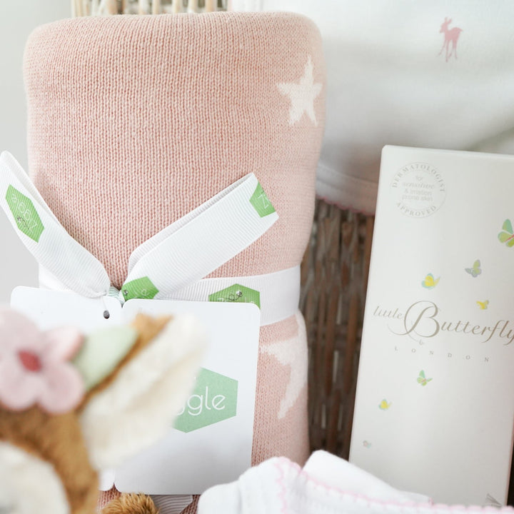 luxury baby hamper with sof cuddly deer with music, luxury white clothing set with pink deer and pink picot edging on sleepsuit, hat and baby bib, soft pink blanket with pale pink stars, white baby slippers with ears, set of four soft blocks with fawn and flowers