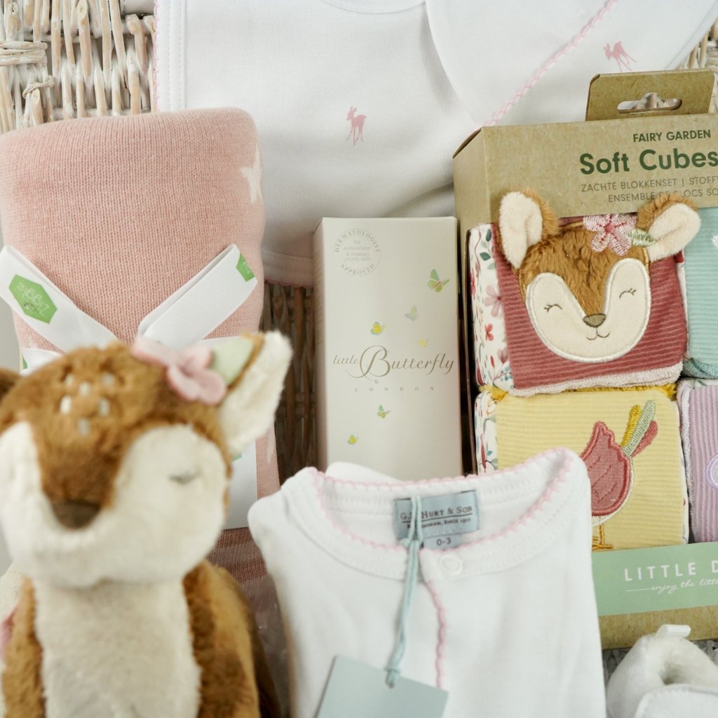 luxury baby hamper with sof cuddly deer with music, luxury white clothing set with pink deer and pink picot edging on sleepsuit, hat and baby bib, soft pink blanket with pale pink stars, white baby slippers with ears, set of four soft blocks with fawn and flowers