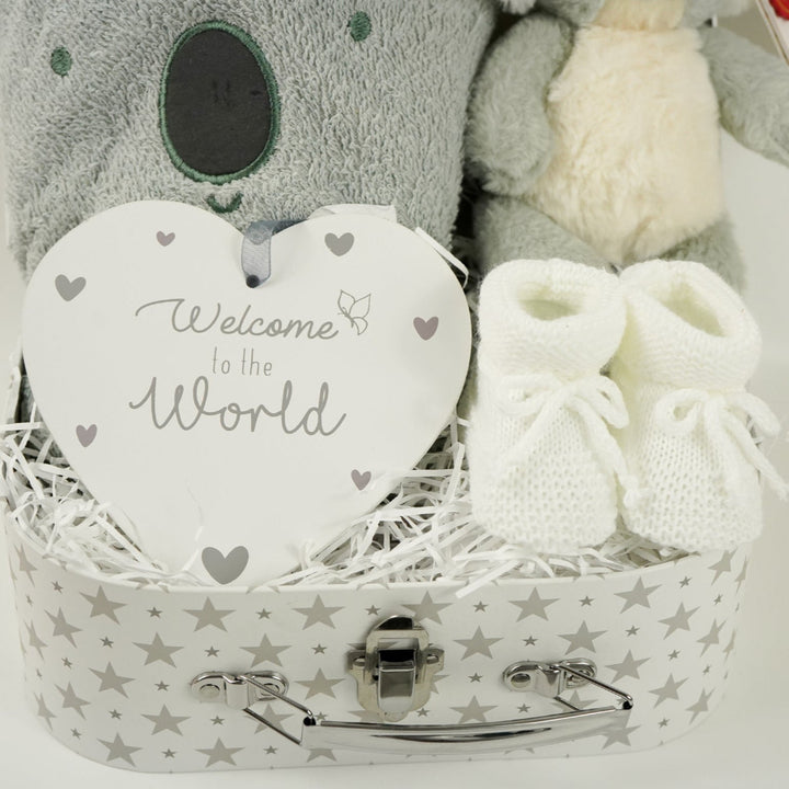 decorative suitcase with baby gifts includes a koala face grey hooded bath towel, Koala soft toy, white knit booties , nursery plaque