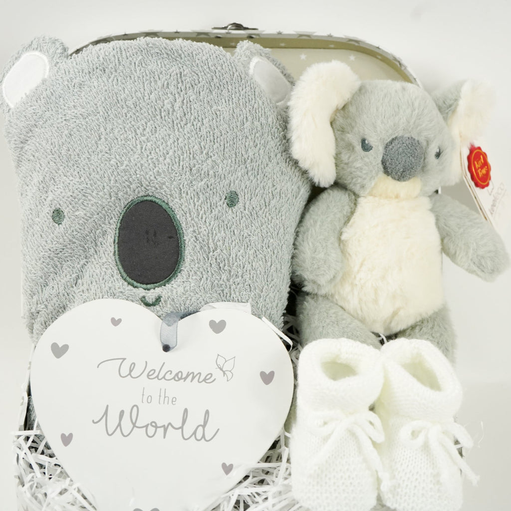 decorative suitcase with baby gifts includes a koala face grey hooded bath towel, Koala soft toy, white knit booties , nursery plaque