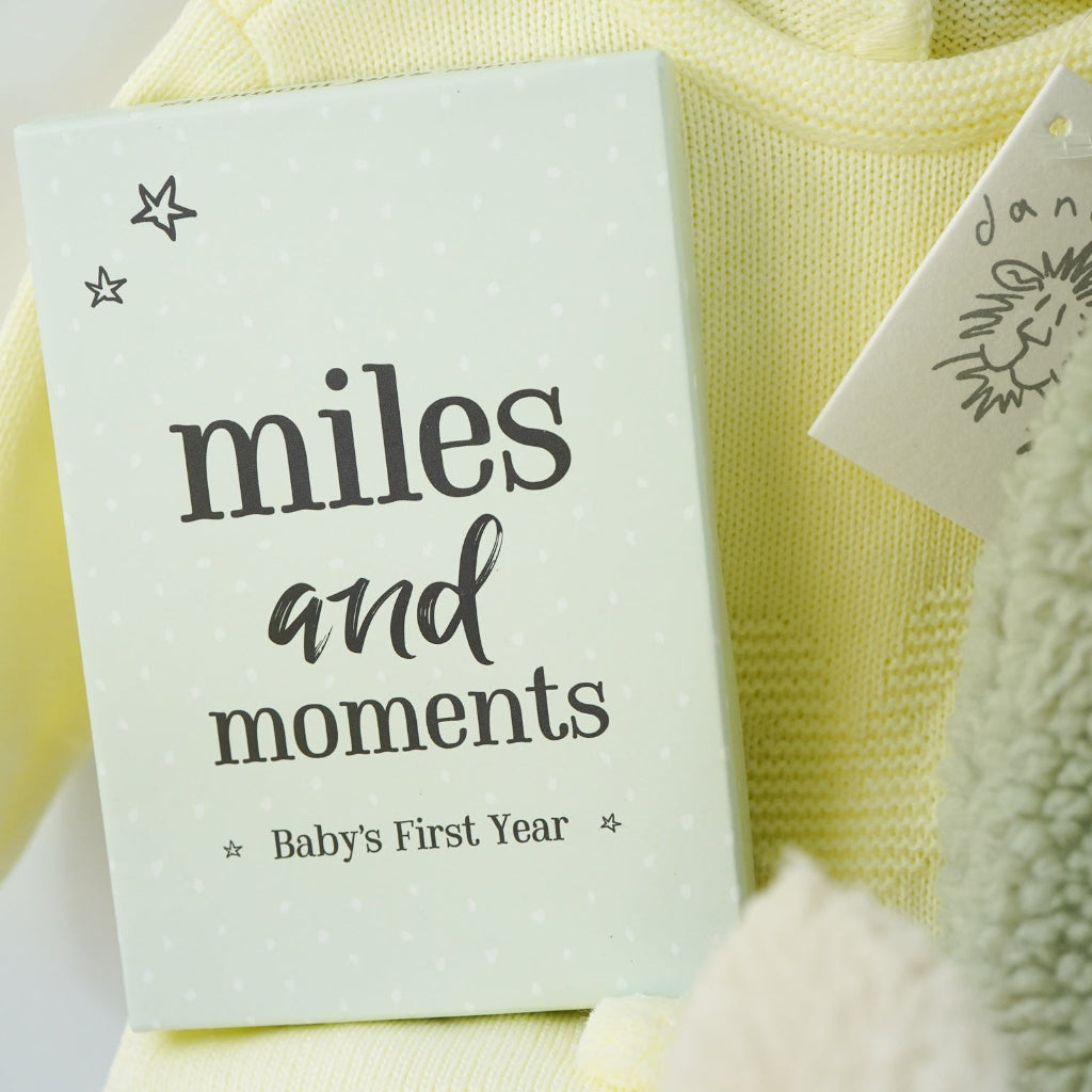 easter baby hamper, yellow knit romper with bunny design and pompom tail, soft fluffy bunny ears green hat with matching bunny ears , booties , recycled cream bunny cuddle toy, miles and moments baby cards, hot chocolate spoon with small eggs