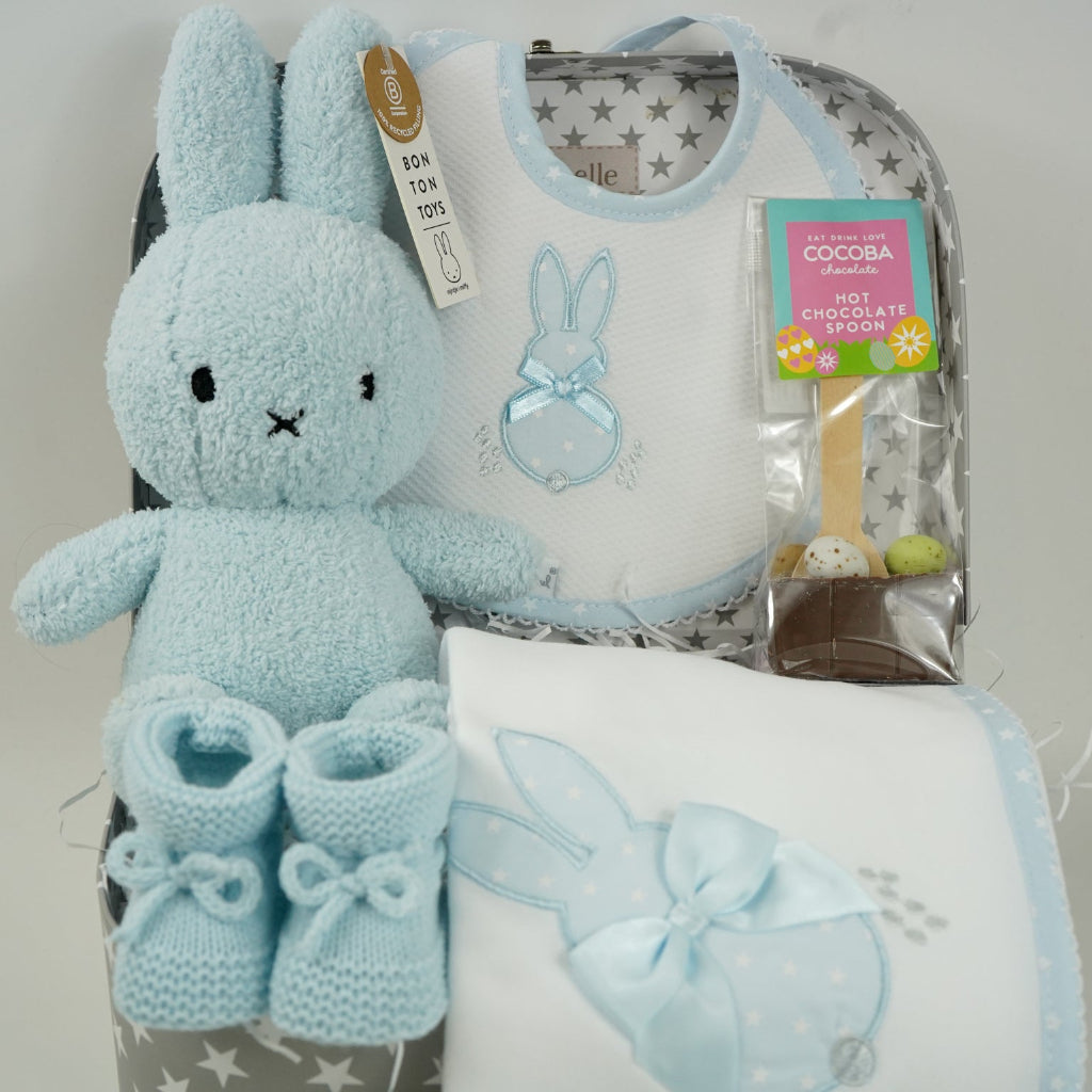 baby case with Blue miffy bunny, white and pale blue baby bib with applique bunny with a ribbon, white wrap with blue applique bunny with ribbon bow, blue knit booties