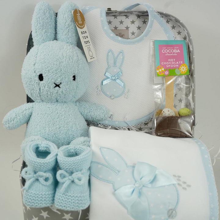 baby case with Blue miffy bunny, white and pale blue baby bib with applique bunny with a ribbon, white wrap with blue applique bunny with ribbon bow, blue knit booties