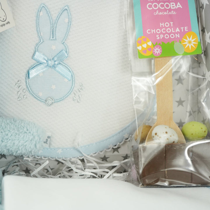 baby case with Blue miffy bunny, white and pale blue baby bib with applique bunny with a ribbon, white wrap with blue applique bunny with ribbon bow, blue knit booties