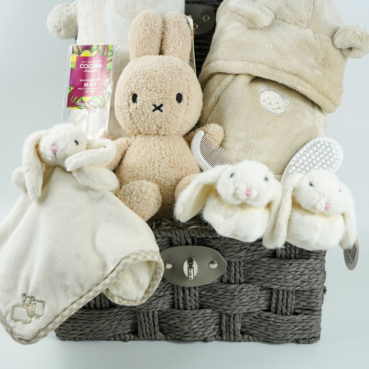 neutral baby gift hamper with  beige and caramel heart blanket with pompoms, baby dressing gown with cute ears, baby bunny slipper and matching bunny comforter, caramel miffy soft toy, chocolate spoon