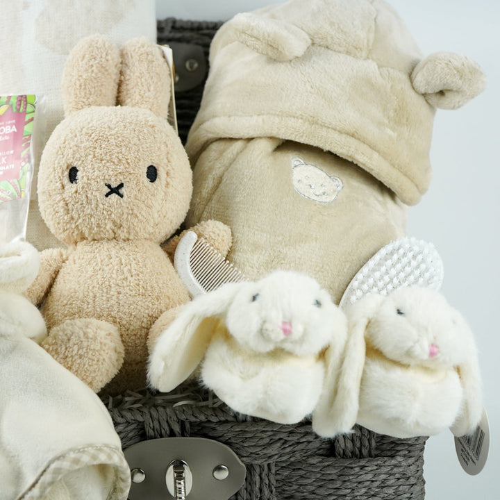neutral baby gift hamper with  beige and caramel heart blanket with pompoms, baby dressing gown with cute ears, baby bunny slipper and matching bunny comforter, caramel miffy soft toy, chocolate spoon