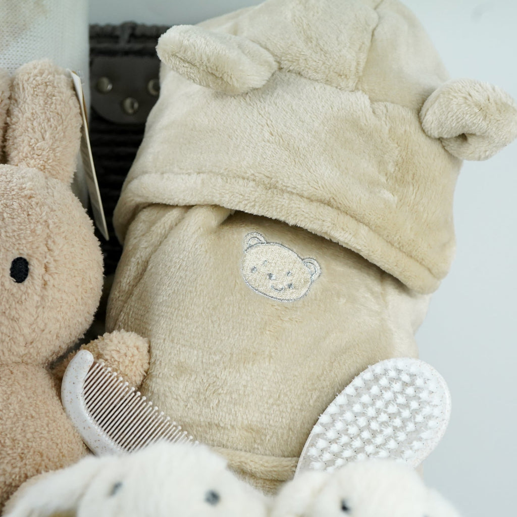 neutral baby gift hamper with  beige and caramel heart blanket with pompoms, baby dressing gown with cute ears, baby bunny slipper and matching bunny comforter, caramel miffy soft toy, chocolate spoon