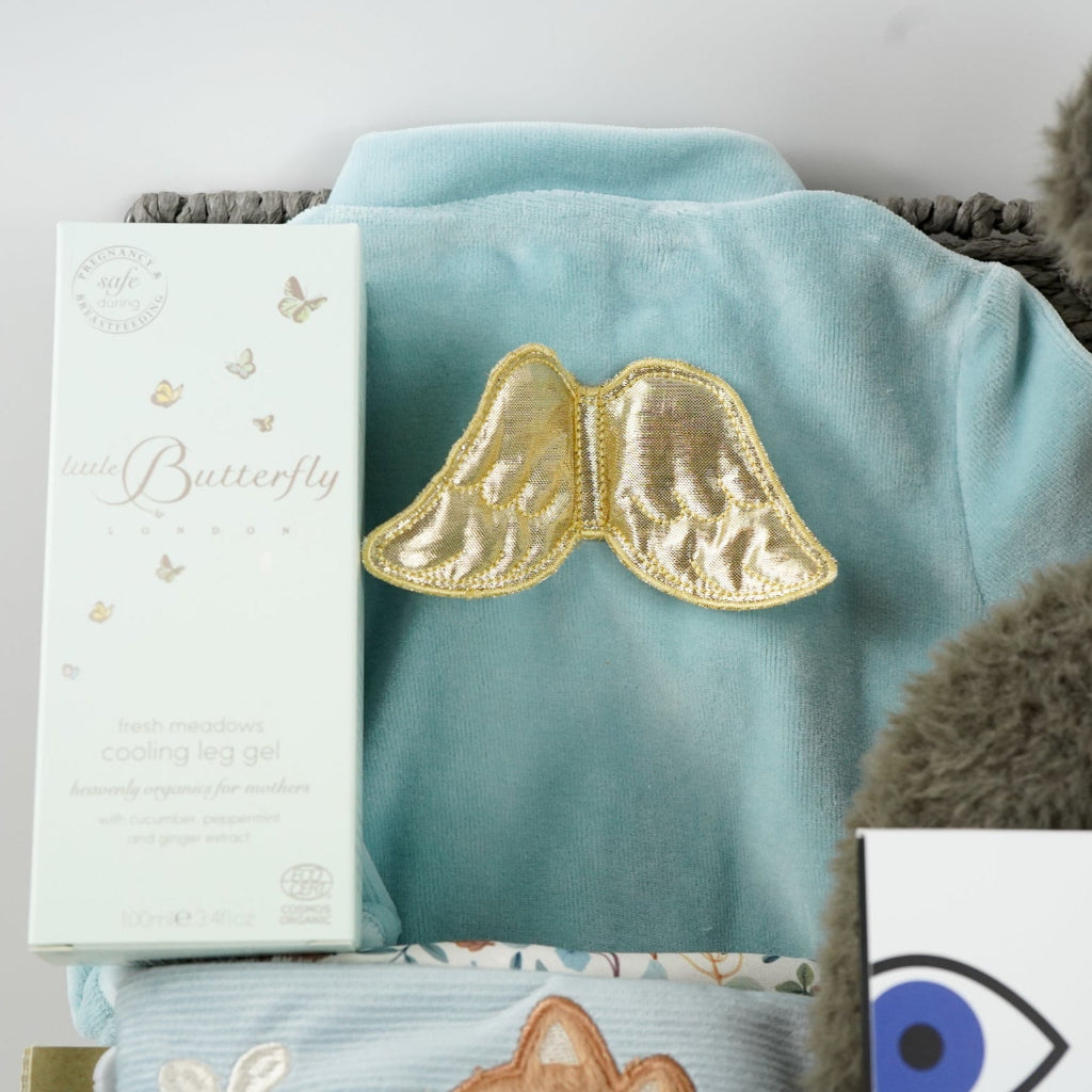 luxury baby hamper, blue velour sleepsuit with gold angel wings, mum toiletries, black and white panda soft toy, black and white sensory flash cards , soft little dutch book, chocolate spoon