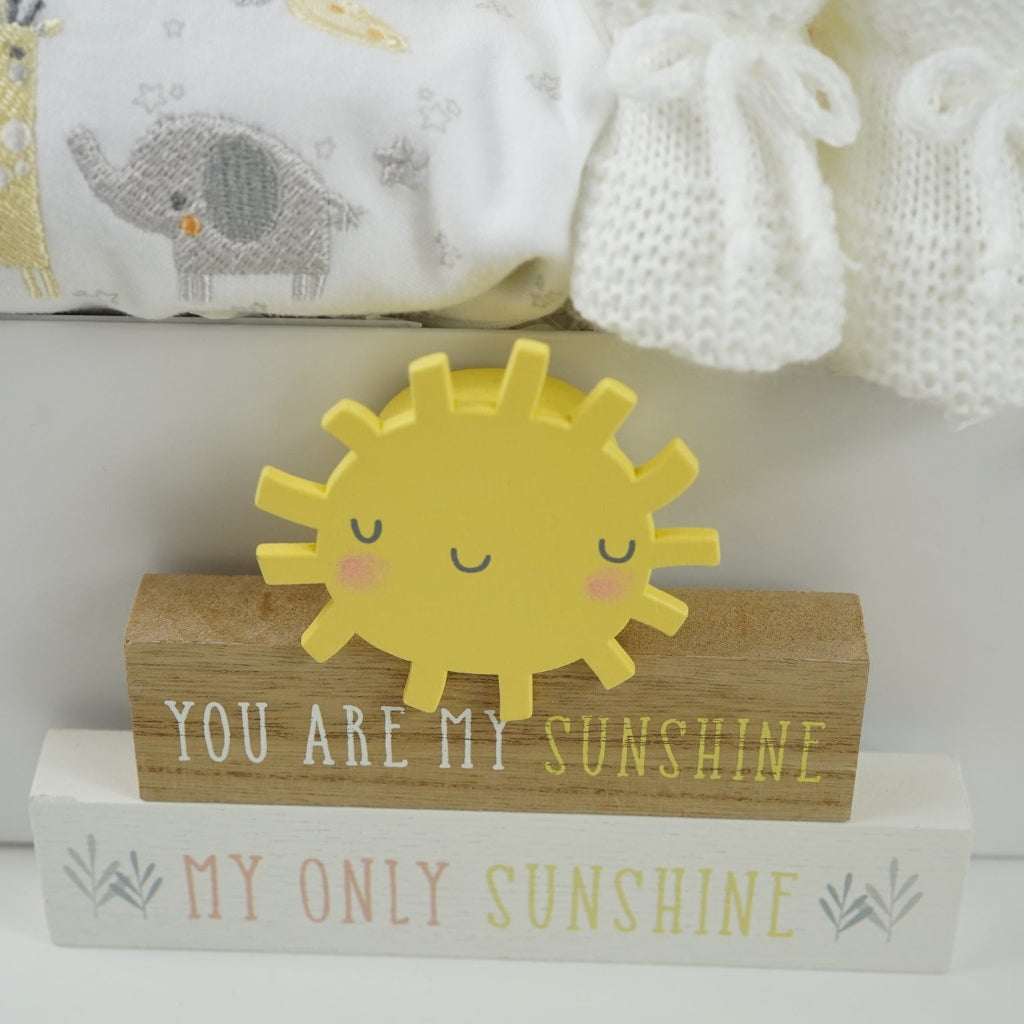 white hamper box with yellow baby dressing gown with duck face hood, soft cuddly yellow duck toy, white muslin square with yellow duck pattern., white knit baby booties, white baby sleep suit with zebra, giraffe and elephant and applique NEWBIE all in grey, yellow and orange, Early years baby journal