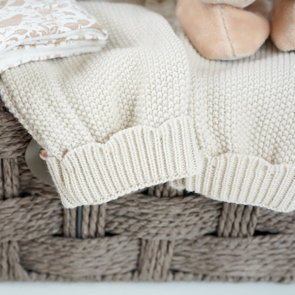 luxury baby girl hamper basket with taupe knitted romper with scalloped edges, cream cellular bamboo and cotton blanket, taupe and dusty pink flopsy bunny comforter , perter rabbit plush slippers , organic baby bubble bath