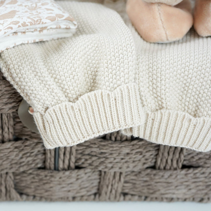 luxury baby girl hamper basket with taupe knitted romper with scalloped edges, cream cellular bamboo and cotton blanket, taupe and dusty pink flopsy bunny comforter , perter rabbit plush slippers , organic baby bubble bath