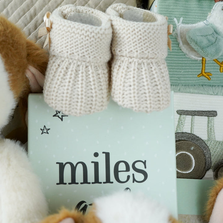 cow themed baby hamper with cow soft toy, comforter and rattle, farmyard soft blocks , baby milestone cards soft biscuit coloured hooded bath towel and knitted booties