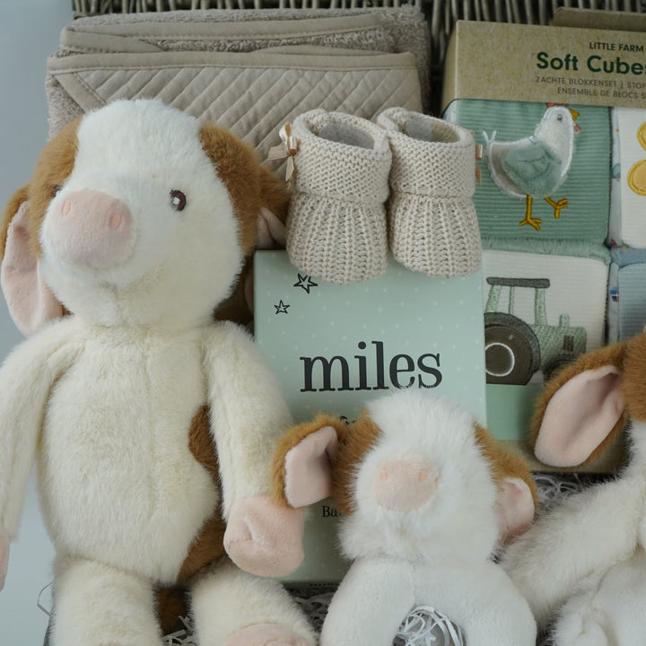 cow themed baby hamper with cow soft toy, comforter and rattle, farmyard soft blocks , baby milestone cards soft biscuit coloured hooded bath towel and knitted booties