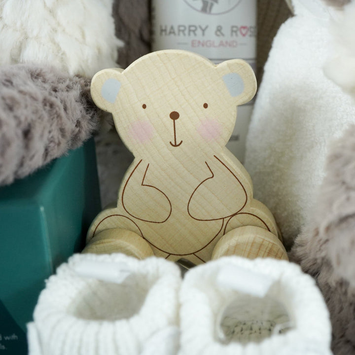 neutral baby hamper with grey and white panda soft teddy and matching baby comforter, cute white baby booties with ears and face, baby wooden push along toy,  baby toiletries, soft hooded towel , luxury boxed candle