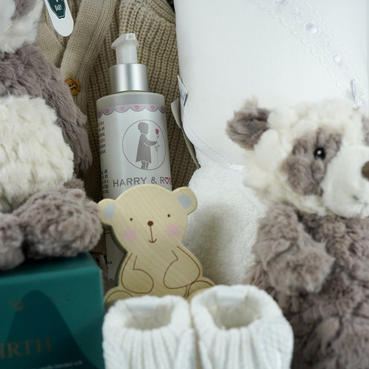 neutral baby gift hamper with grey and white panda soft teddy and matching baby comforter, cute white baby booties with ears and face, baby wooden push along toy,  baby toiletries, soft hooded towel , mum candle gift in a box