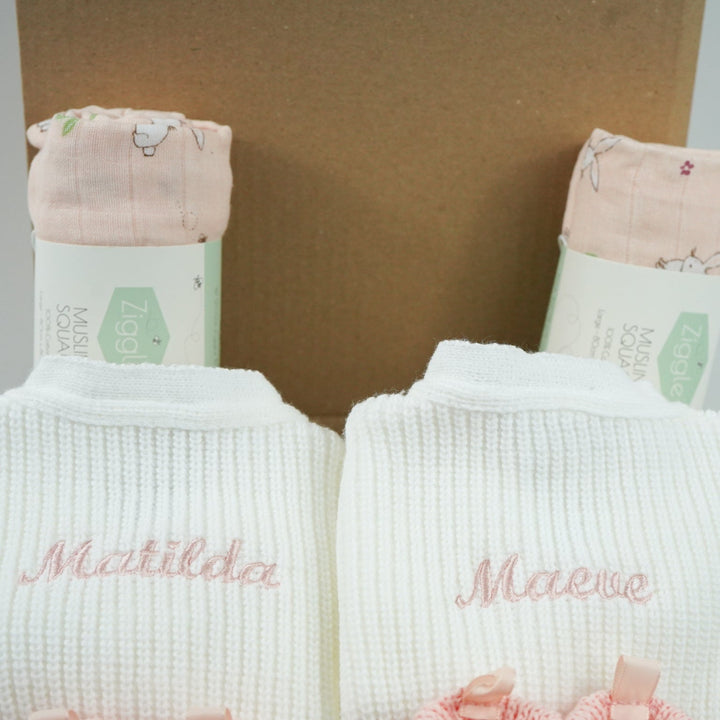baby gifts in a eco friendly outer box includes white knit baby ribbed cardigans x 2 and pink booties with bows x 2 and pink muslin squares with bunnies x 2