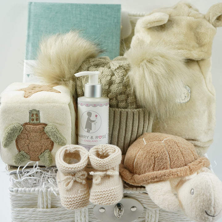 neutral baby hamper with baby dressing own, booties , baby journal, fluffy double pom pom hat, activity cube in neutral green, brown and cream with turtle, star fish and seahorse , soft turtle rattle toy