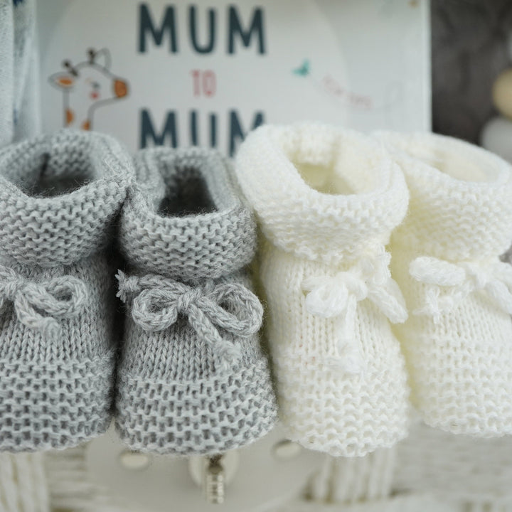 luxury baby gifts in white basket baby journal, organic baby blanket, organic snow bear baby romper, 2 pairs of baby booties, muslin, wooden staging toy and grey soft baby bear