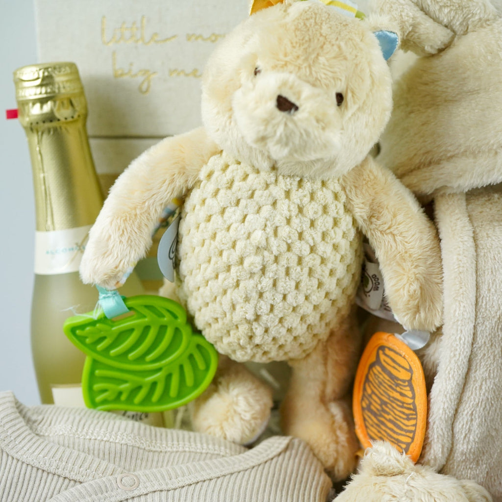 Grey paper rope neutral baby hamper with winnie the pooh comforter and pram toy, baby hooded dressing gown in caramel colour and baby sleepsuit, baby organic bubbles, non alcoholic freixenet and milestone cards