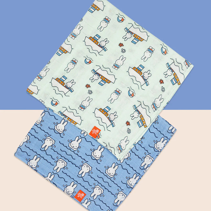 White storage suitcase with soft blue terry Miffy, pale blue knit booties with tie, salted caramel chocolate stirrer, two muslins with Miffy pattern, bucket sunhat for baby with Miffy pattern