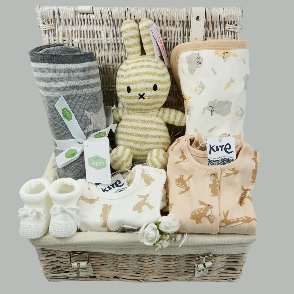 white wicker basket, grey star cotton baby blanket, gold and cream organic miffy, cream baby bodysuit with brown rabbits, caramel coloured sleepsuit with brown rabbit