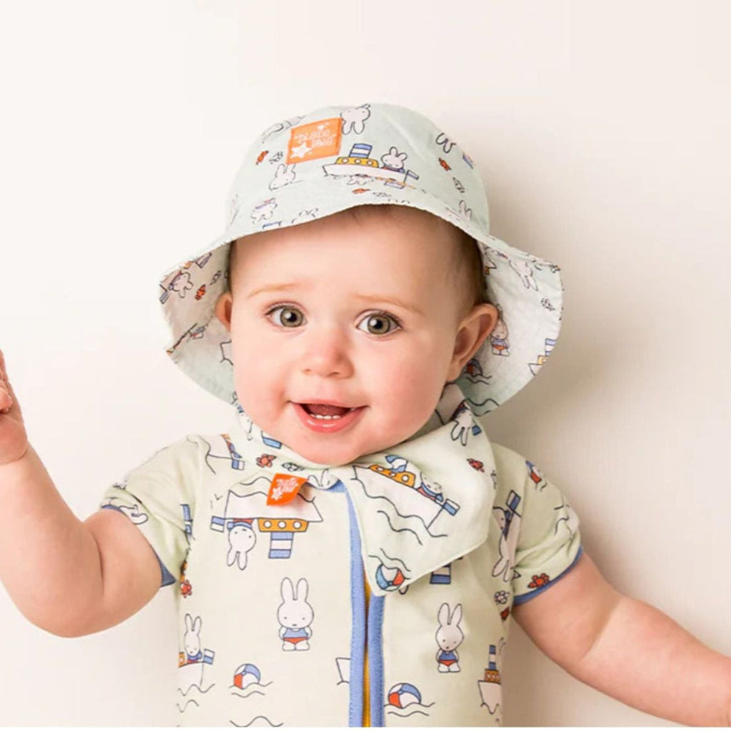 White storage suitcase with soft blue terry Miffy, pale blue knit booties with tie, salted caramel chocolate stirrer, two muslins with Miffy pattern, bucket sunhat for baby with Miffy pattern