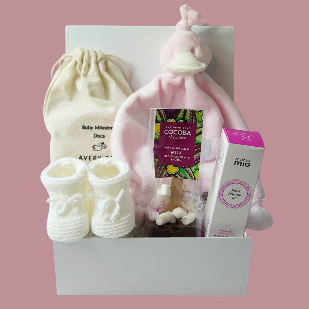 pregnancy hamper with wooden pregnancy milestone discs in a draw string bag, white knit booties, pink BamBam duck tuttle,  perineum oil