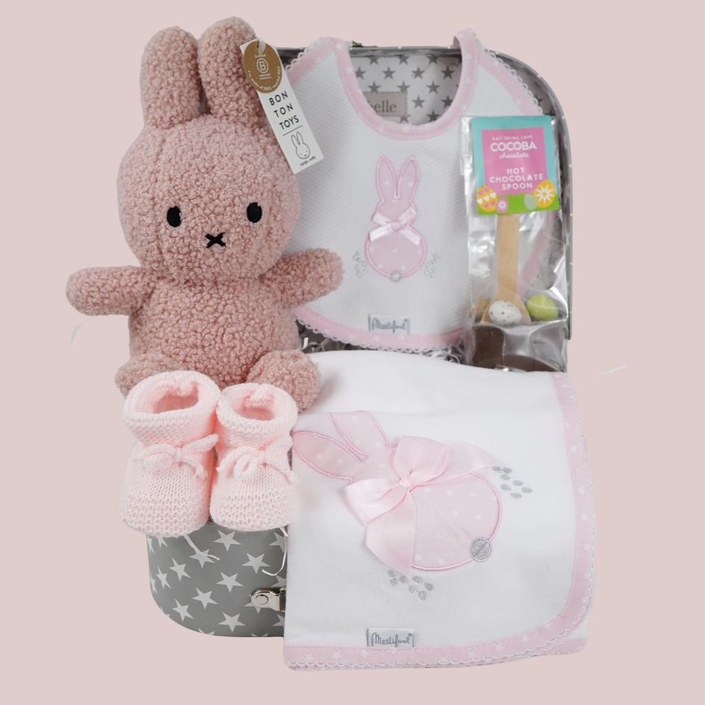 baby keepsake trunk with pink Miffy teddy, white bib with pink scalloped edge and applique bunny design , matching white wrap with pink edging and bunny applique design, pink booties , chocolate sppon with easter eggs