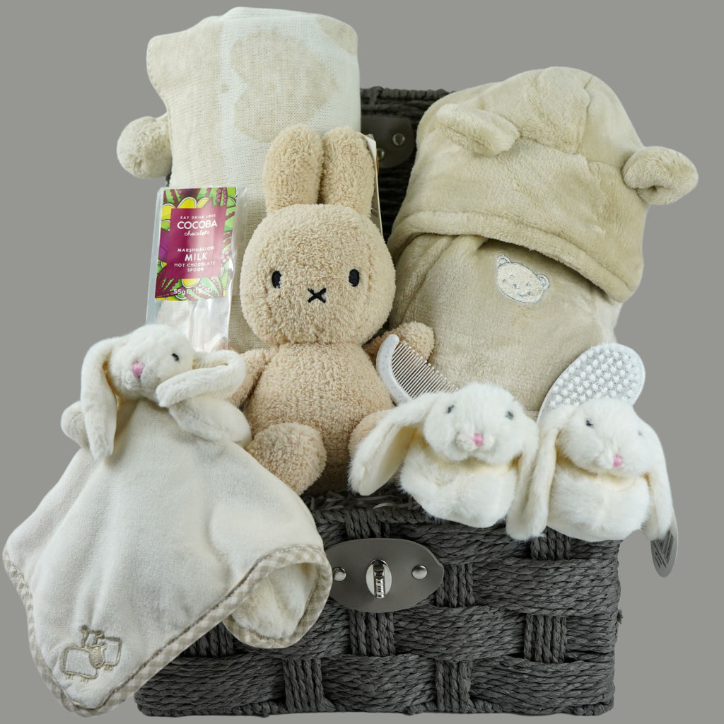 neutral baby gift hamper with  beige and caramel heart blanket with pompoms, baby dressing gown with cute ears, baby bunny slipper and matching bunny comforter, caramel miffy soft toy, chocolate spoon