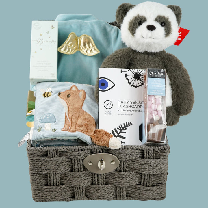 luxury baby boy hamper, mum toiletries, dusty blue velour angle wing sleepsuit , black and white baby sensory flash cards , soft fabric forest friends animal activity book, soft panda toy, chocolate stirrer spoon