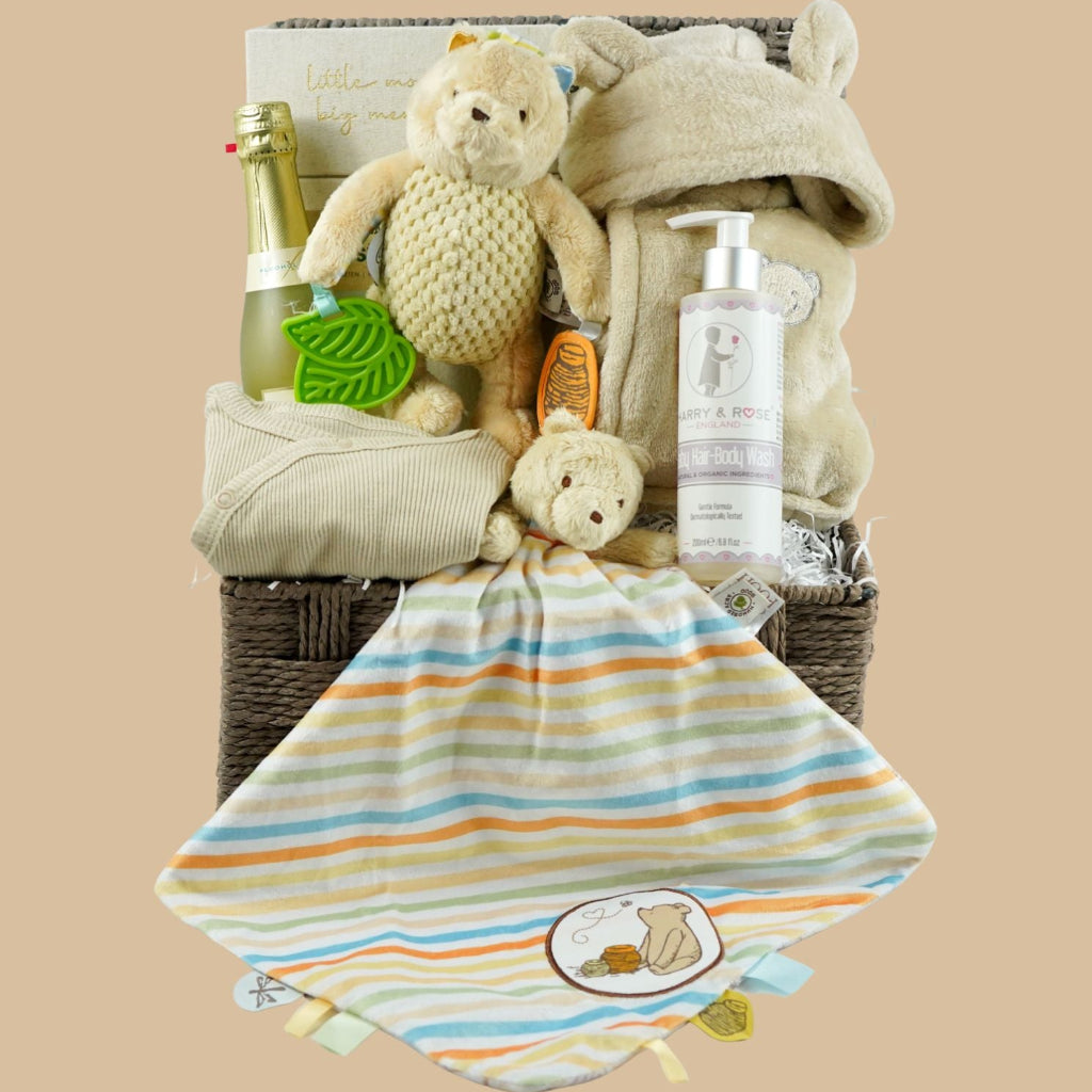 Grey paper rope neutral baby hamper with winnie the pooh comforter and pram toy, baby hooded dressing gown in caramel colour and baby sleepsuit, baby organic bubbles, non alcoholic freixenet and milestone cards