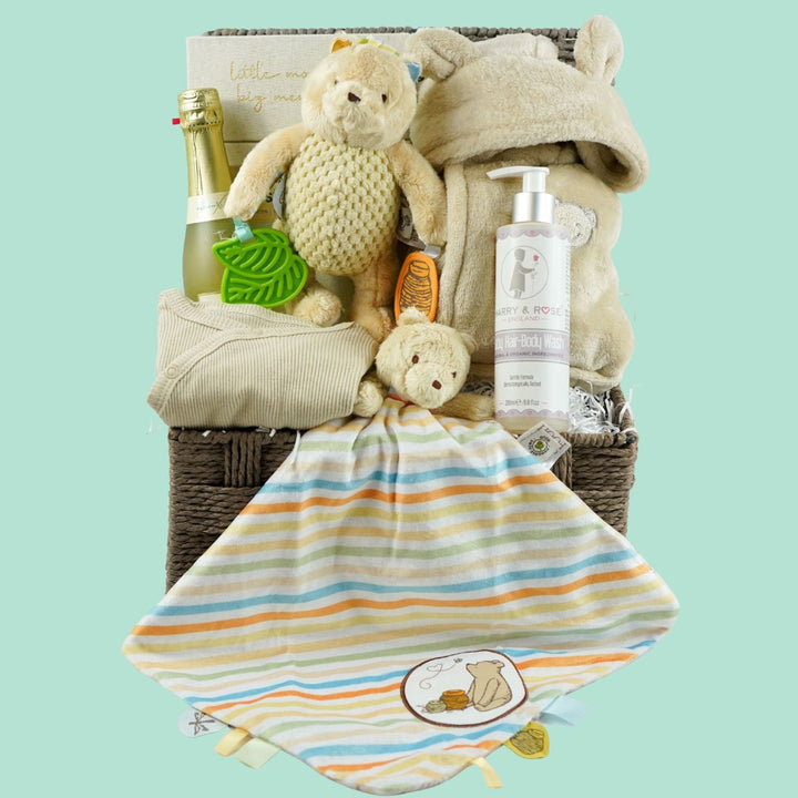 Grey paper rope neutral baby hamper with winnie the pooh comforter and pram toy, baby hooded dressing gown in caramel colour and baby sleepsuit, baby organic bubbles, non alcoholic freixenet and milestone cards