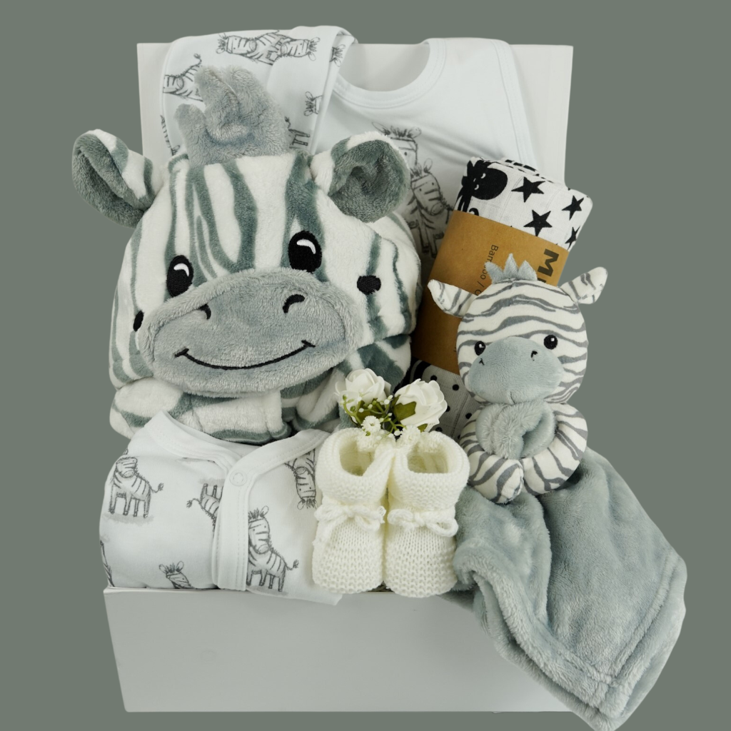 white hamper box with baby dressing gown with zebra faced hood, white baby sleepsuit with zebras, white baby hat with zebras, grey and white baby comforter with a zabra head, white knit baby booties, black and white sensory muslin swaddle and