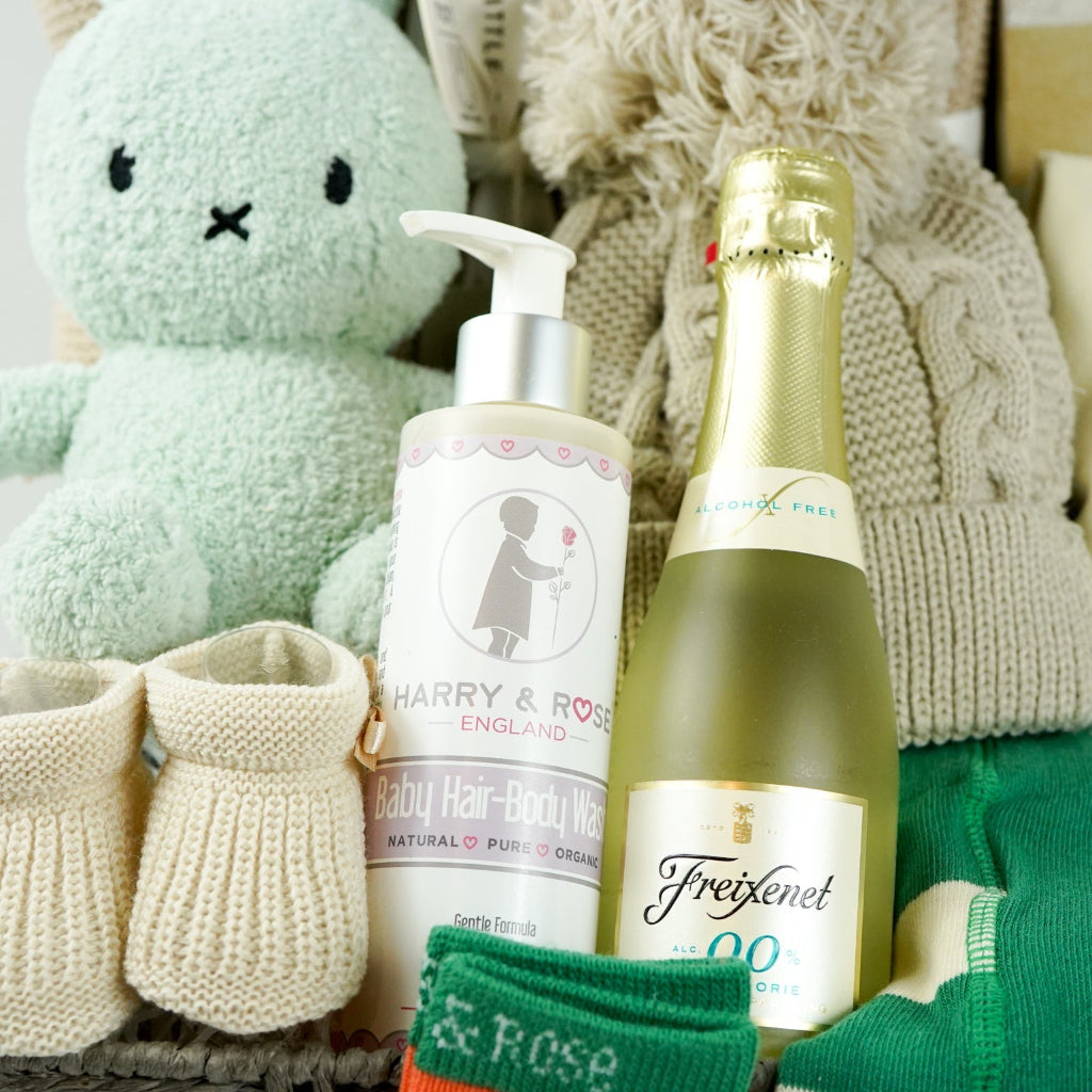 grey hamper baby basket with light green miffy, organic beige blanket, organic baby pompom hat, Little Dutch baby milestone cards, biscuit coloured nit booties, organic baby wash, mify organic clothing set includes a long sleeved tshirt, knit leggings with miffy on the bum, miffy socks , non alcoholic prosecco