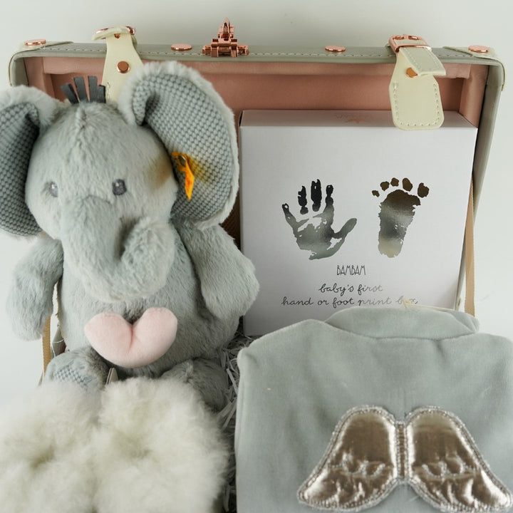 Grey baby suitcase with Steiff grey musical elephant, white alpaca wool baby slippers , grey with silver angel wings baby velour sleepsuit, baby handprint set