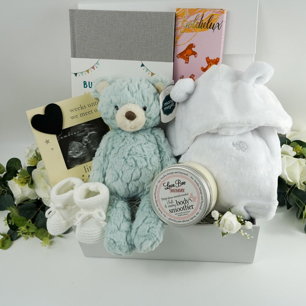 antenatal  pregnancy hamper with baby scan photo frame , pale blue/green soft baby teddy, pregnancy and first year of life journal in a grey cover, cute white baby dressing gown with cute ears, white knit baby booties, fairy tale inspired chocolate
