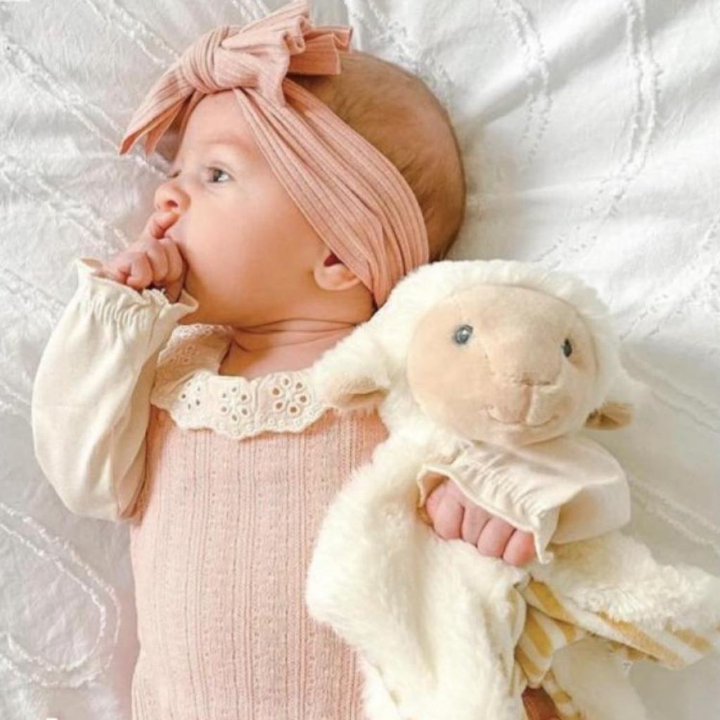 soft fluffy lamb head on a fluffy cream comforter