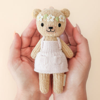 Knitted teddy bear with a floral headband next to a decorative box with floral patterns