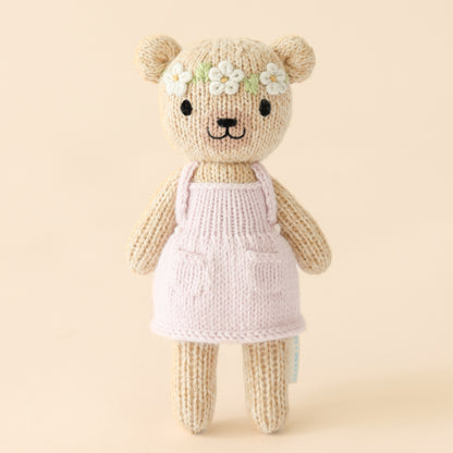 Knitted teddy bear with a floral headband next to a decorative box with floral patterns