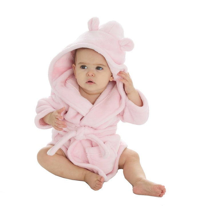 Baby in a pink hooded robe sitting on a white background