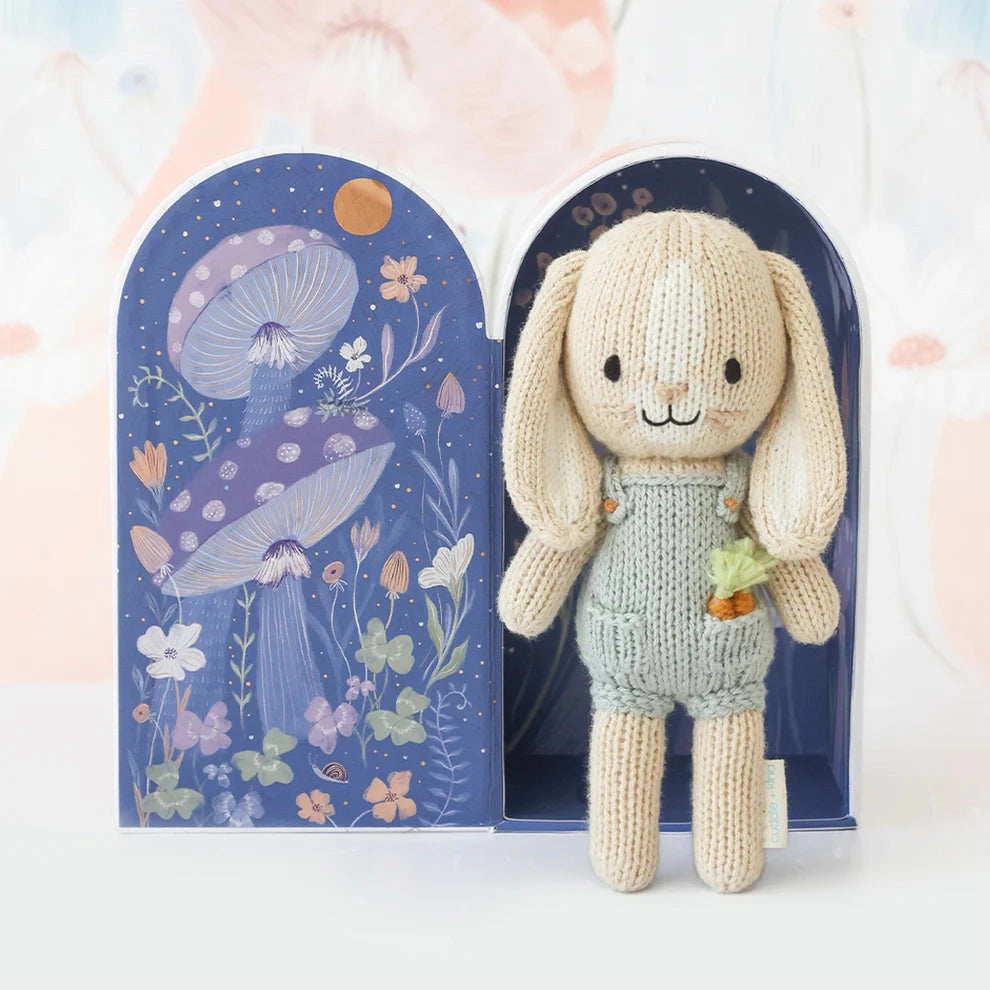 Knitted toy rabbit with a carrot in his pocket and light blue dungarees