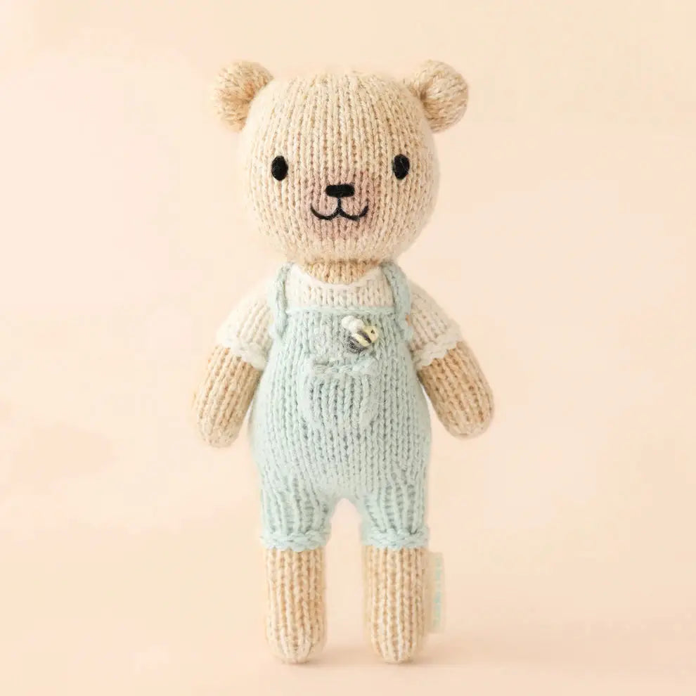 tiny charlie hand knitted bear in pale blue dungaree's with a honey bee