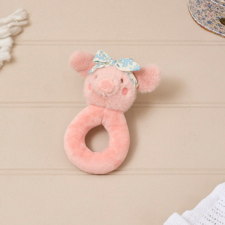 Pink plush toy with a bow on a wooden surface